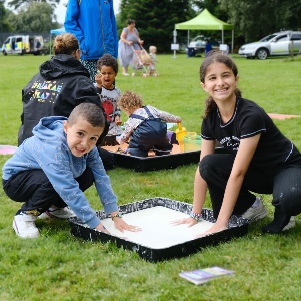 Two children with hands in gloop